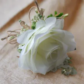 a buttonhole featuring lily of the valley & a white or ivory silk rose